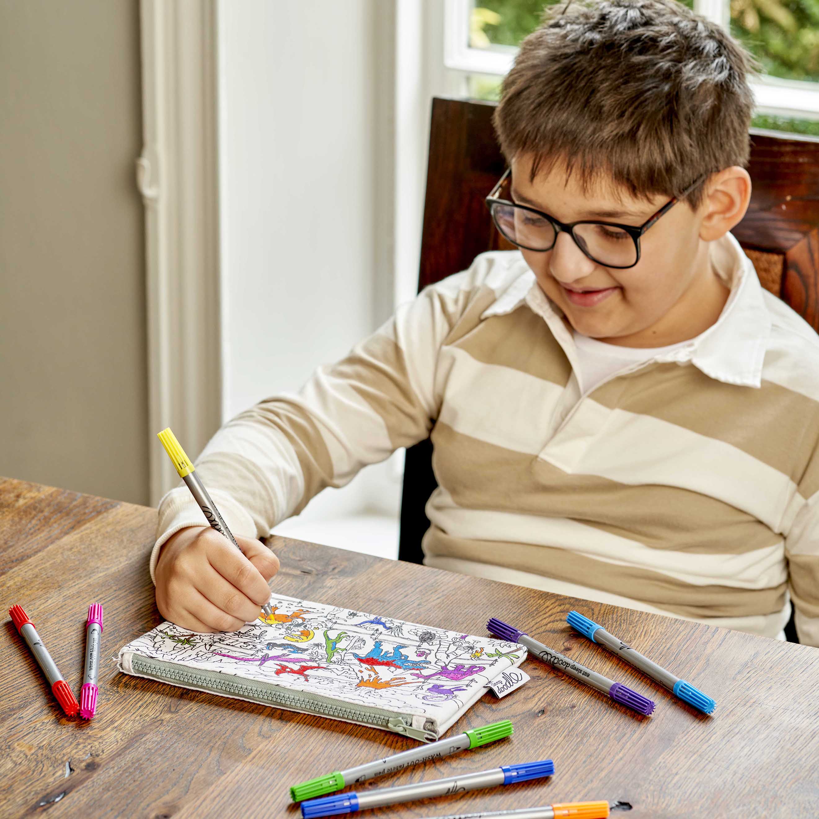 boy in brown shirt colouring in pencil case