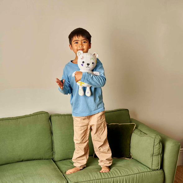 boy standing on sofa holding colour in artie bear