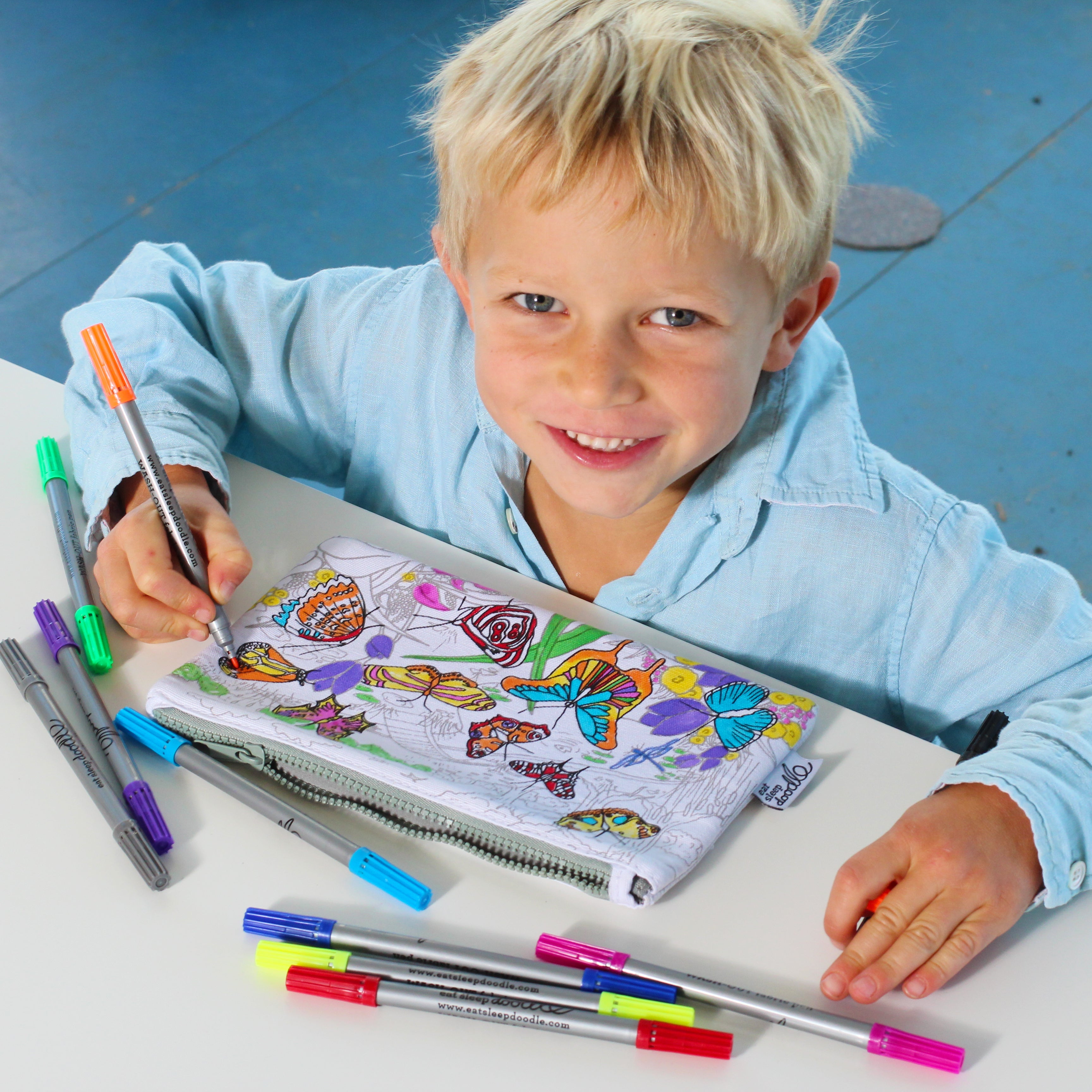 young boy smiling at camera whilst colouring in